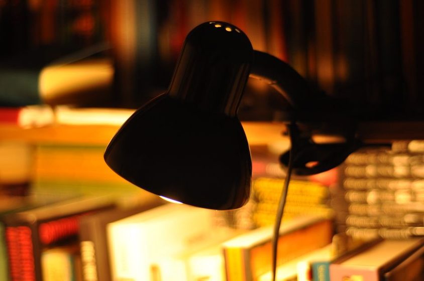 A dim living room in the evening with a lamp and a closed book